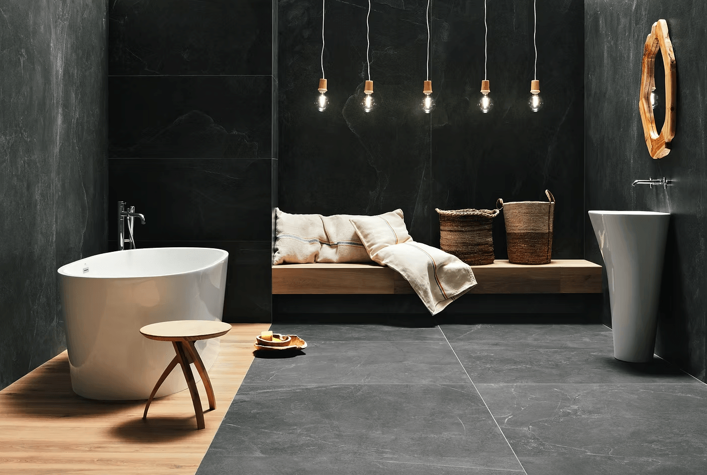 Modern bathroom with freestanding bathtub, wooden bench, and hanging lights.