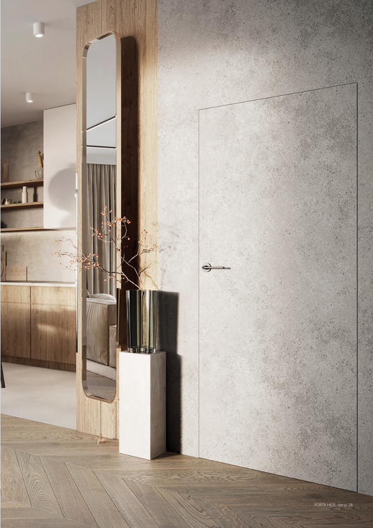An interior door with a modern design, featuring a textured white panel in a room with wooden flooring and a reflective surface.